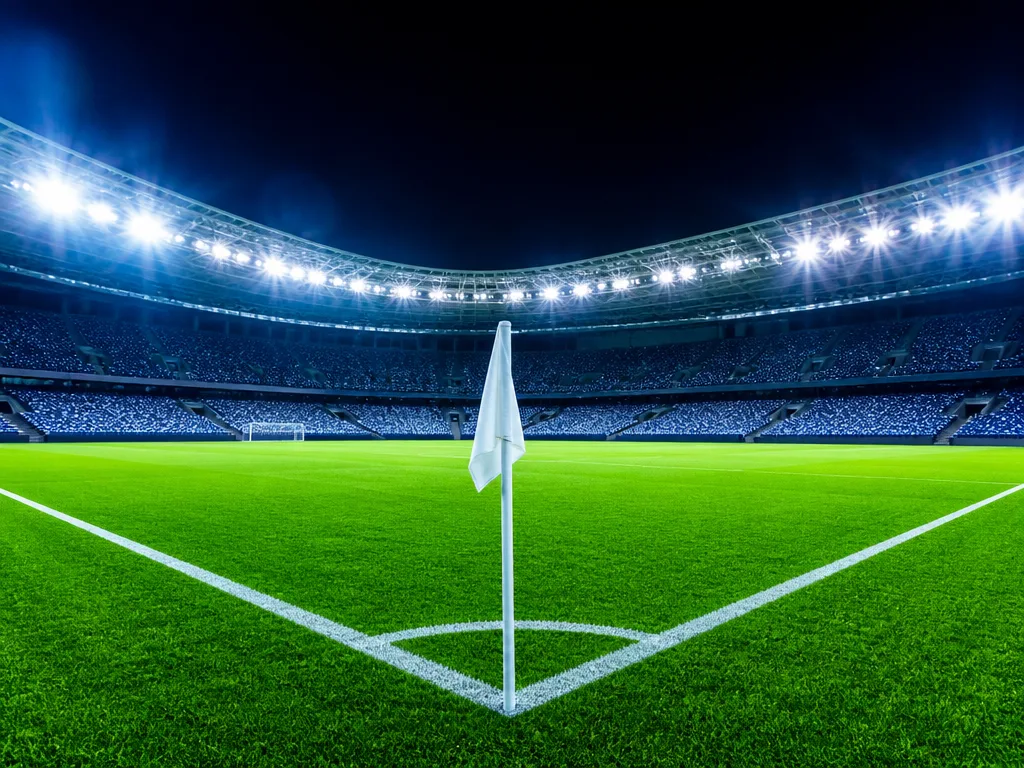 Fotbollsarena under strålkastarljus på kvällen med tom grön plan
