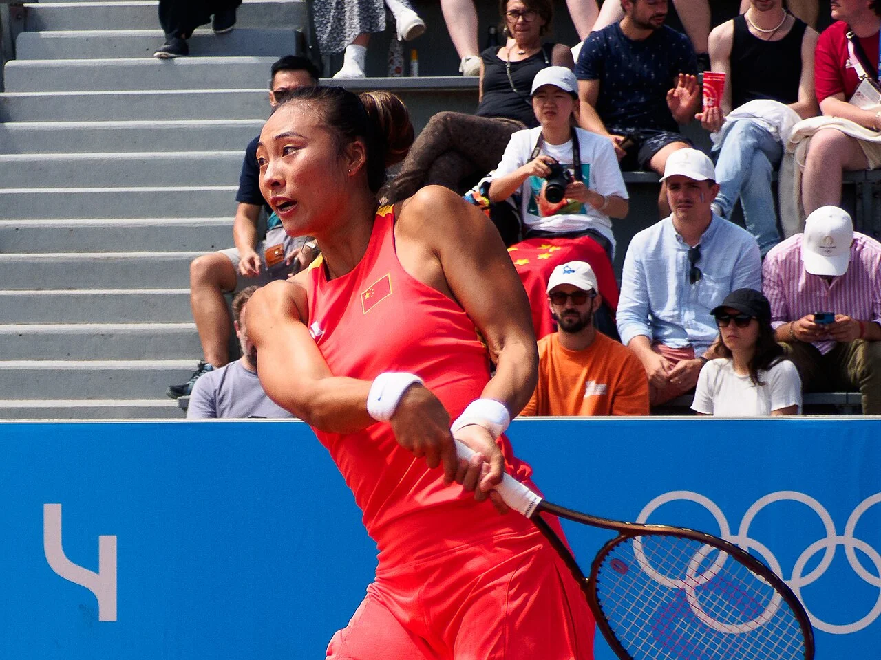 Zheng Qinwen slår en forehand i röd matchdräkt under OS-turneringen i tennis i Paris 2024